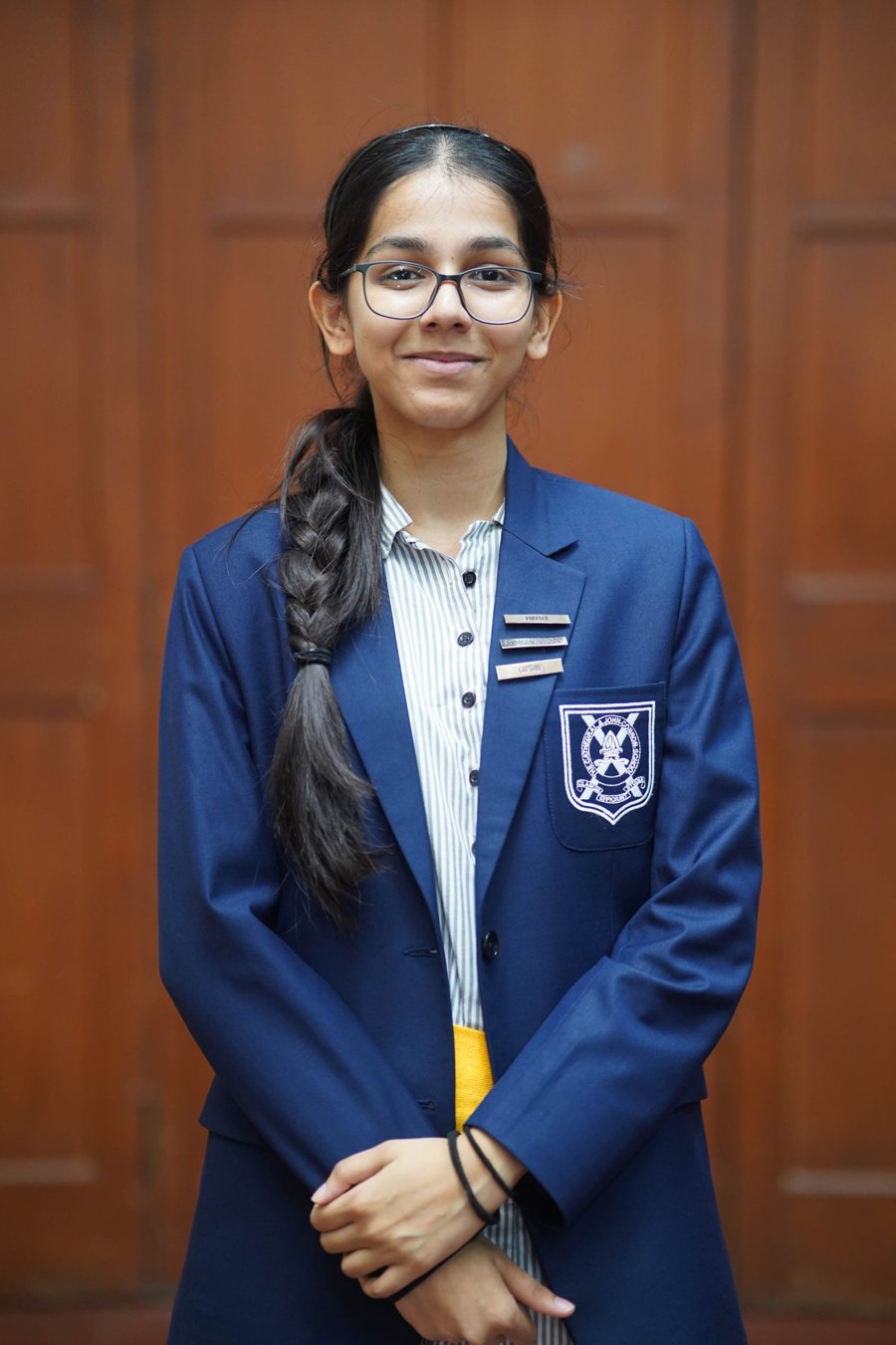 Inaya Vora in her school blazer with Prefect, Symposium President and Captain badges